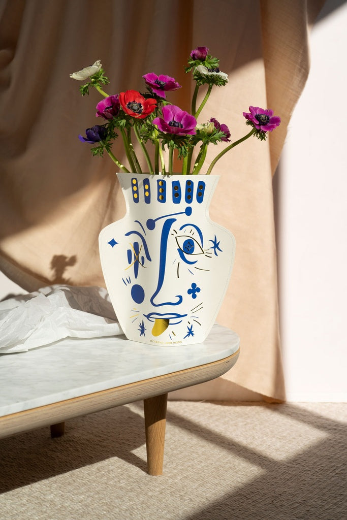 Flower paper vase with the drawing of a face in blue and gold, a collaboration between Spanish award-winning designer Jaime Hayon and Octaevo. Available at www.cuemars.com