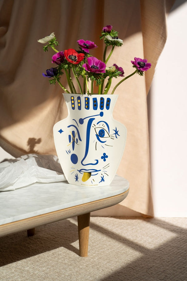 Flower paper vase with the drawing of a face in blue and gold, a collaboration between Spanish award-winning designer Jaime Hayon and Octaevo. Available at www.cuemars.com