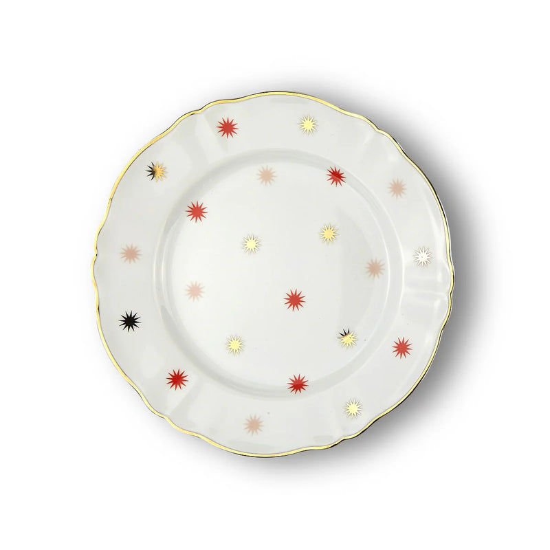 Porcelain dinner plate from Bitossi Home’s Abracadabra collection, showcasing a bold, multicolored starburst pattern with asymmetrical design elements and refined gold detailing around the rim.
