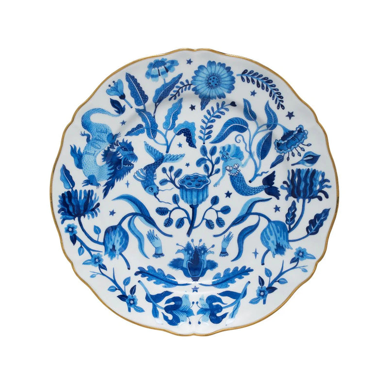Decorative dinner plate from Bitossi Home's Fabula collection featuring intricate blue illustrations of a dragon, mermaid, birds, and floral motifs on a white background, with a scalloped edge and gold trim.