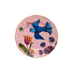 Fruit plate from Bitossi Home's Fabula collection featuring a whimsical blue bird with heart-tipped feathers flying over colorful flowers and golden stars on a pink background, with a scalloped edge and gold trim.