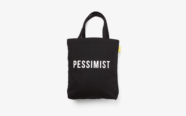 Black cotton tote bag with the typography Pessimist in white by the School of Life. 