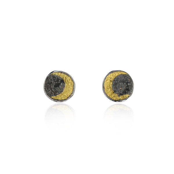 Details of the craters on a 23kt gold plated crescent moon disc earrings on the black night sky made of oxidised sterling silver. Handcrafted by London based jeweler Momocreatura. 