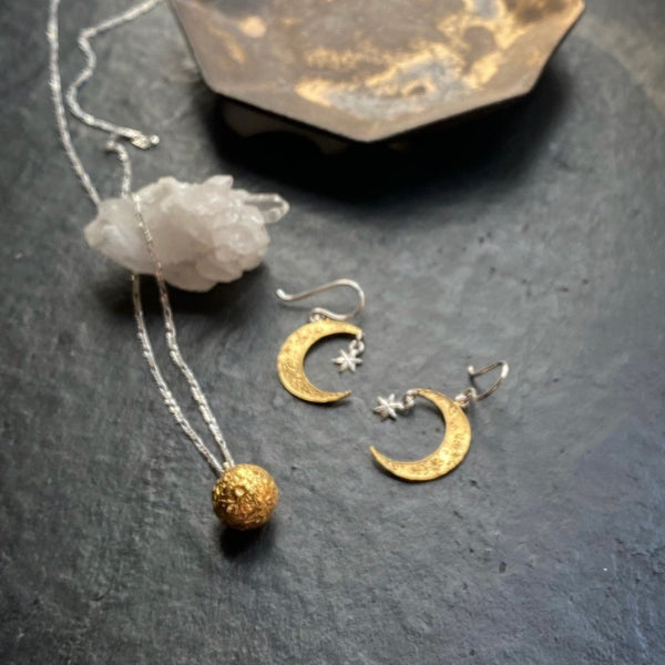 Detailed gold plated crescent moon earrings with hand carved craters and a pendant silver star. Gold plated full moon sphere necklace with a silver chain. Designed and made by Momocreatura in London.