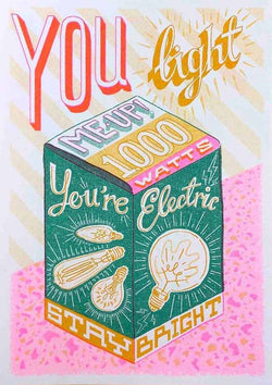 a greenm yellow, pink and orange light bulb box with the typography You Light Me Up - 1000 Watts - You're Electric - Stay Bright, by British illustrator Jacqueline Colley