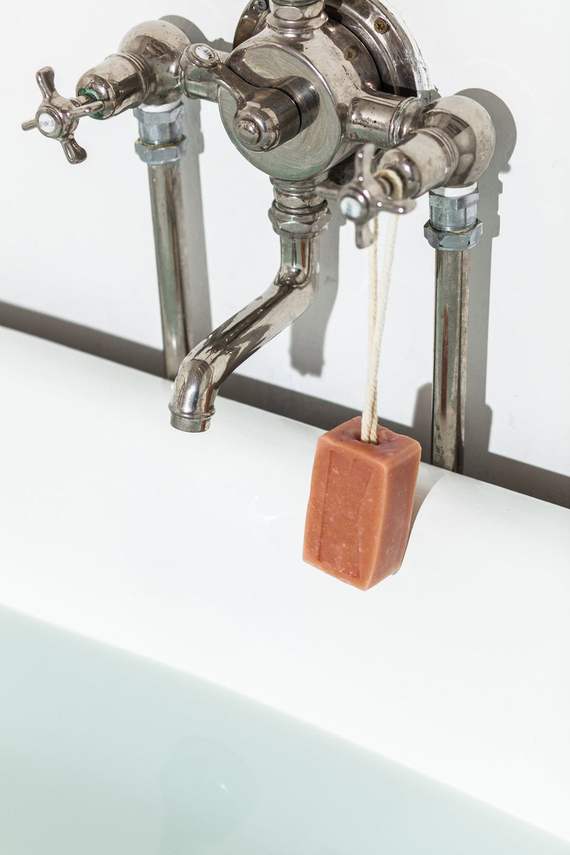 French Pink Clay exfoliating soap on a cotton rope hanging from the bathtub by natural skincare brand Kleen soaps ideal for sensitive skin