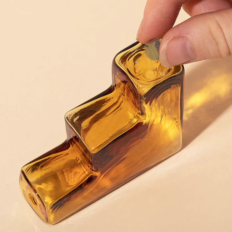 Mesh Screen being placed on a brown glass pipe by American based company Laundry Day, available at www.cuemars.com