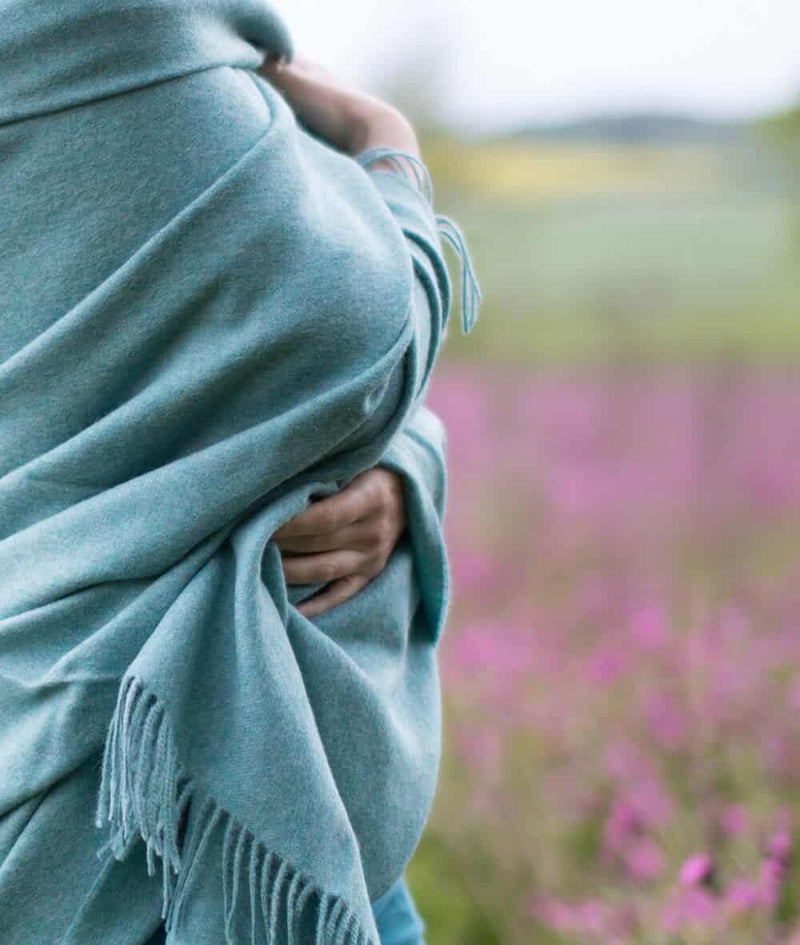 lifestyle picture of handmade super soft baby alpaca throw by so cosy in pastel blue melange available online and at the store