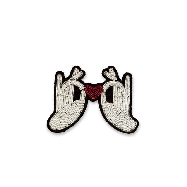 two white hands holding a red heart embroidered in white and red by French company Macon et Lesquoy. Available at www.cuemars.com