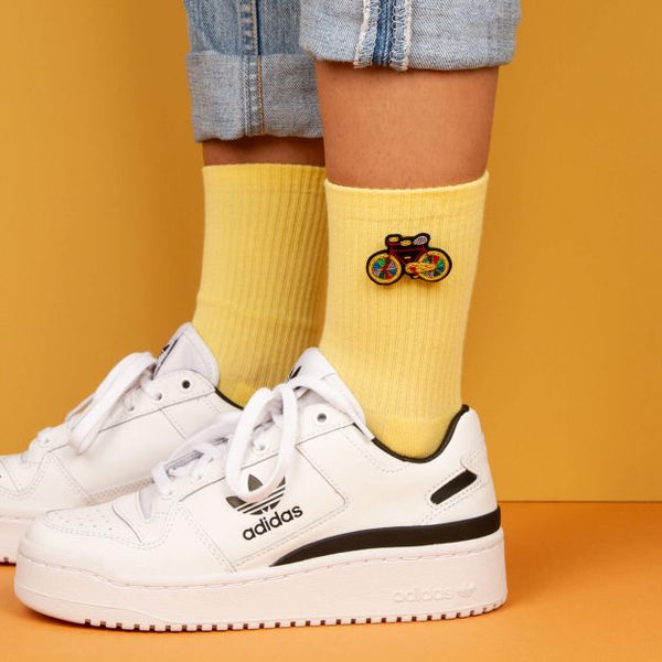 Colourful bike embroidered in yellow, red, blue and green by Macon et Lesquoy. Handmade brooch on bright yellow socks and a pair of white adidas trainers. available at www.cuemars.com