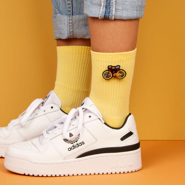 Colourful bike embroidered in yellow, red, blue and green by Macon et Lesquoy. Handmade brooch on bright yellow socks and a pair of white adidas trainers. available at www.cuemars.com