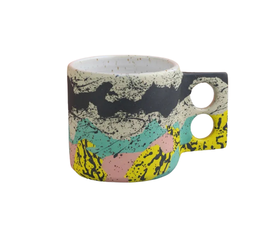 Colourful coffee mug with a geometrical handle with two holes for the fingers by Minx Factory, available at cuemars.com
