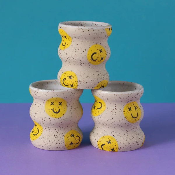 Wavy coffee cups without handles with yellow smiley faces. Designed and handmade by Minx Factory and sold at cuemars.com