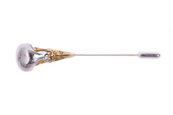 Close up details of a handmade bird skull lapel pin in sterling silver with a gold plated beak