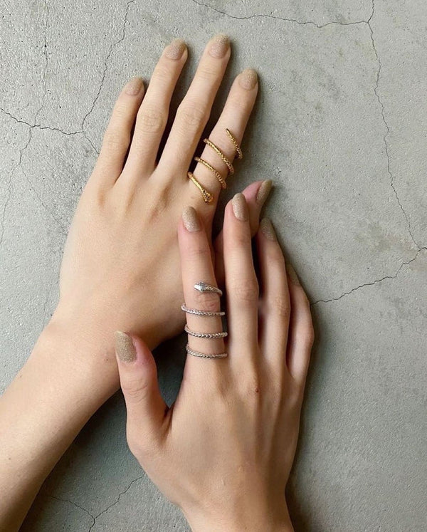 Two Hands wearing two statement snake rings, one in silver, one in gold. By Momocreatura London