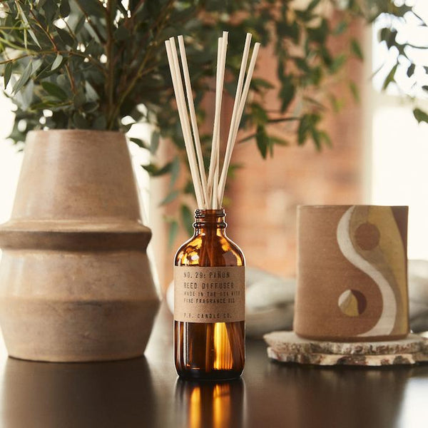 pinon reed diffuser in amber glass by pf candle co  on a table