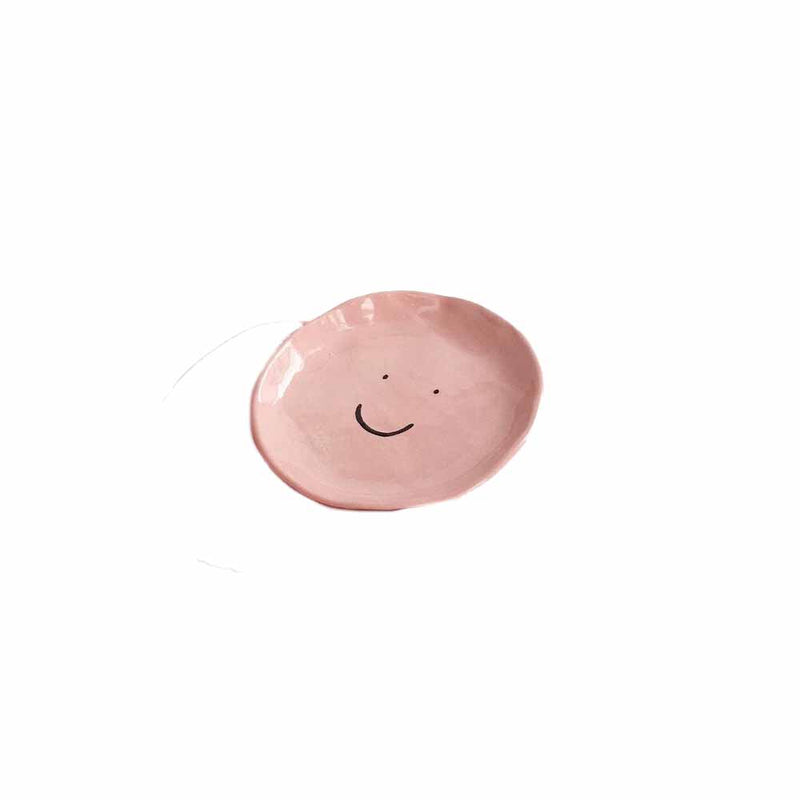 Pink ceramic dish with a black smiley face by illustrator Amy Victoria Marsh, available at www.cuemars.com