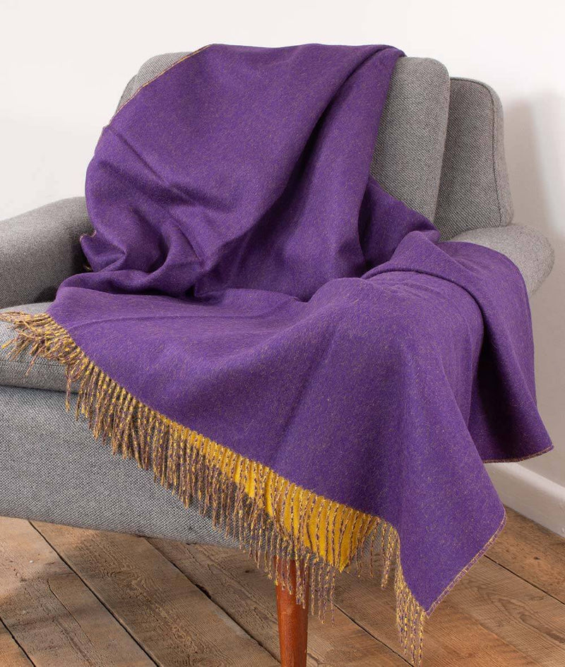 Lifestyle picture of Woven purple and yellow reversible Baby Alpaca soft blanket designed in the UK by So Cosy