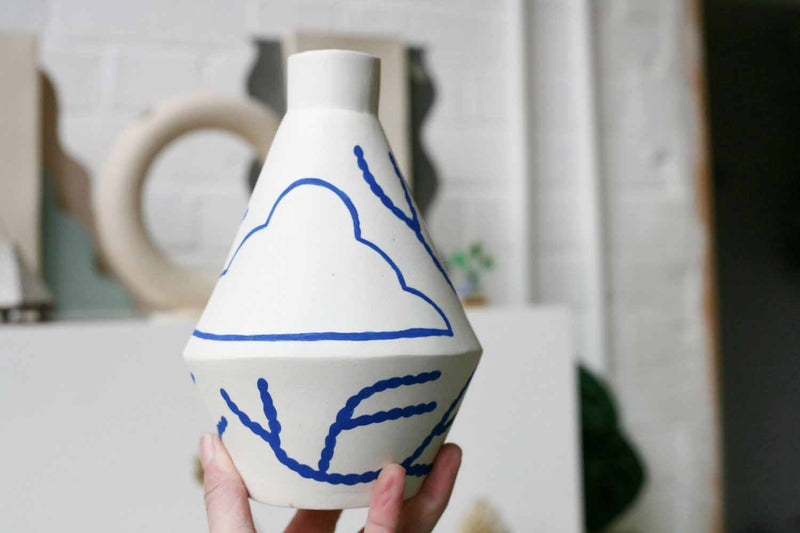 handmade diamond shaped porcelain vase with blue motifs by ceramicist Sophie Alda, available at cuemars.com
